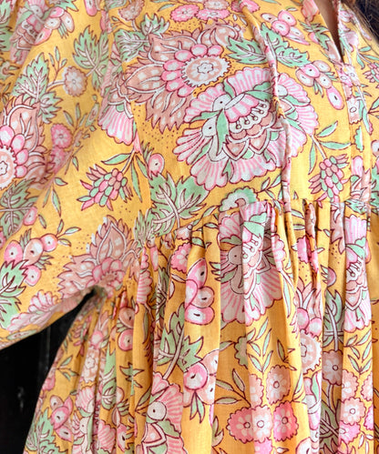 Close-up of green and pink floral motifs on yellow cotton fabric